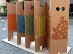 four cardboard boxes with designs on them sitting in front of a tree and building structure