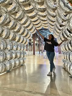 a woman is standing in front of a large amount of silver rims on display