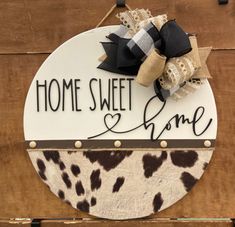 a sign that says home sweet home with a cow print bow on the front door