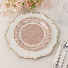 a white plate sitting on top of a table next to silverware and pink flowers