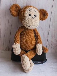 a crocheted monkey sitting on top of a black suitcase with the words crochet pattern below it