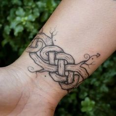 a person's arm with a tattoo on it and a chain attached to the wrist