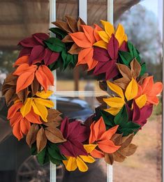 a wreath made out of felt leaves sitting in front of a window