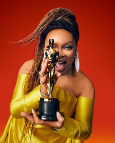 a woman holding an award in her hand and making a funny face while posing for the camera