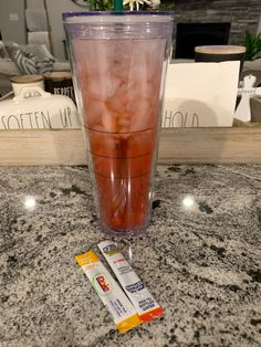 a drink and two packets of toothpaste sitting on a counter