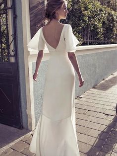 a woman in a white dress is walking down the street with her back to the camera