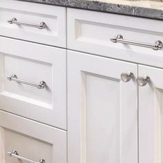 a kitchen with white cabinets and marble counter tops