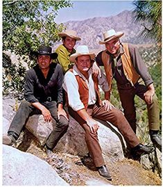 four men are posing for a photo on the side of a mountain