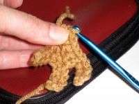 someone is crocheting a small stuffed animal in a zippered pouch with a needle