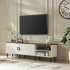 a living room with a large tv on top of a wooden entertainment center next to a plant