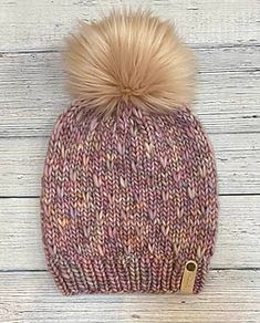 a knitted hat with a pom - pom sitting on top of it