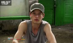 a young man sitting on the ground wearing a hat