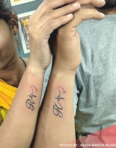 two people with matching tattoos on their arms, one holding the other's arm