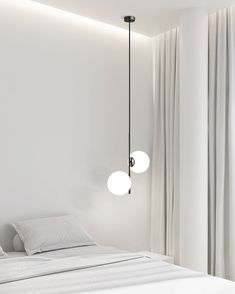 a bed with two lights hanging from it's headboard in a white room