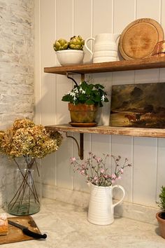 the shelves are filled with flowers and other kitchen items, including plants in vases