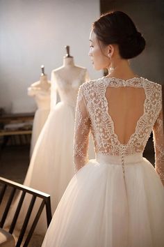 the back of a woman's wedding dress in front of mannequins