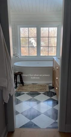 an open door leading to a bathroom with a checkered floor and white bathtub