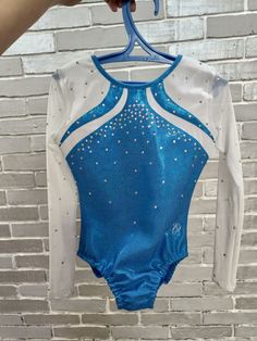 a person holding up a blue and white gymnastics leotard