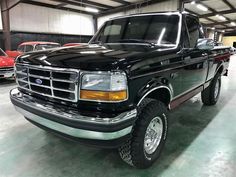 a black truck parked in a garage next to other cars