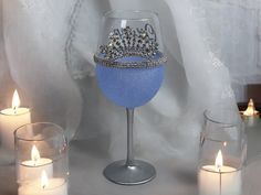 a wine glass with a tiara on it next to candles