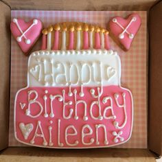 a birthday cake decorated with pink icing and white frosting in a cardboard box