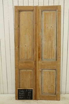 an old wooden door with a chalkboard in front of it and a white wall behind it