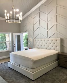 a white bed sitting in a bedroom under a chandelier