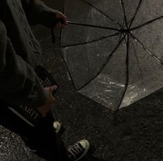 a person holding an open umbrella on the ground with their feet in the rain,