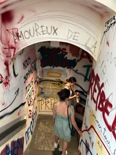 two women standing in a graffiti covered tunnel