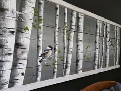 a bird is perched on a tree branch in front of a wall hanging with birch trees