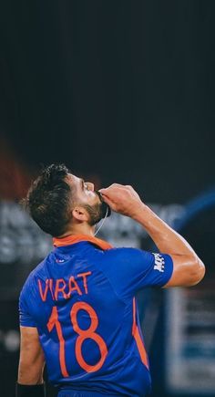 a man in blue jersey drinking from a bottle