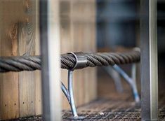 a close up of a metal bar on a wooden bench with roped ends and wood planks in the background