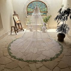 a wedding dress is hanging in front of a window with an arched doorway and potted plant