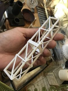 a hand holding a model of a building made out of white plastic and some other items