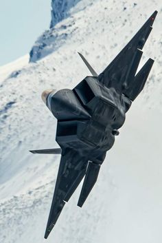 a fighter jet flying through the air over snow covered mountains