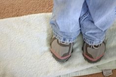 a person standing on top of a white rug next to a pair of blue jeans