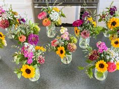 several vases filled with different types of flowers on a counter top in front of a stove