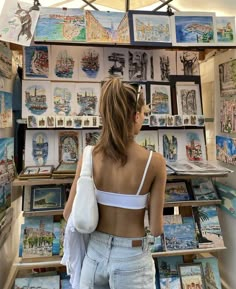 a woman standing in front of a wall with pictures and paintings on it's walls