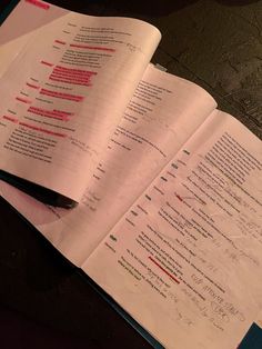 an open book sitting on top of a table next to some papers with writing on them