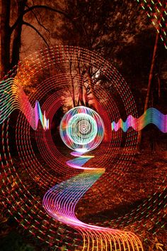 colorful lights are projected on the ground in front of trees and grass, with long exposure