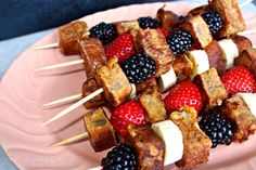 several skewers filled with fruit on top of a pink plate