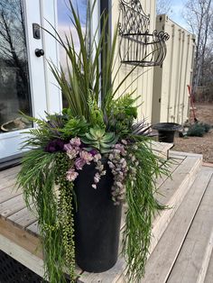 a large potted plant sitting on top of a wooden deck next to a door