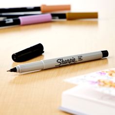 three pens sitting on top of a wooden table