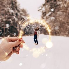 a person holding a circular object in the snow with lights on it's side