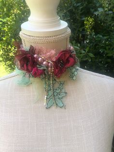 a white mannequin with red flowers and beads on it's neckline