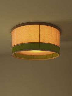 a lamp hanging from the ceiling in a room with a green shade on it's side