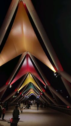 people are walking under an unusual structure at night