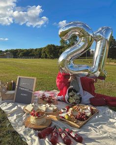 a large number balloon sitting on top of a table filled with food and drinks in front of a field