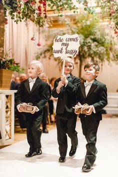 three young boys dressed in tuxedos holding signs