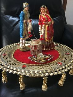 two figurines standing on a table in front of a black leather chair with red carpet